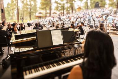 view of audience from onstage and looking from behind the pianist sitting at the piano.