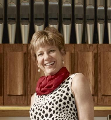 Concert organist Faythe Freese standing in front of organ pipes