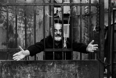 Sergei Parajanov with outstretch arms behind bars.