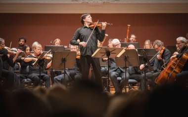 Joshua Bell playing his violin centered around the Academy of St Martin in the Fields musicians.