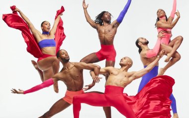 Alvin Ailey dancers jumping and doing tricks in red, purple, and pink dancewear.