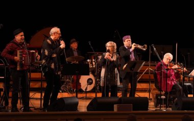 Itzhak Perlman and In the Fiddler's House performers on stage playing their instruments.