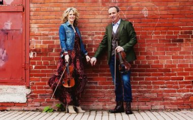 Natalie MacMaster and Donnell Leahy holding hands while holding their violins.