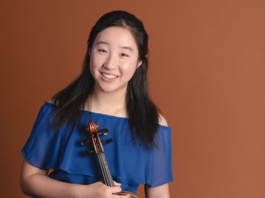 Violinist Charisse Chao in a blue dress against a rust background