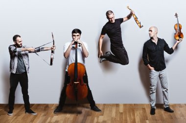The members of Invoke Quartet are posing with their instruments against a white wall