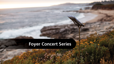 A music stand on a path above the beach with the text, "Foyer Concert Series"