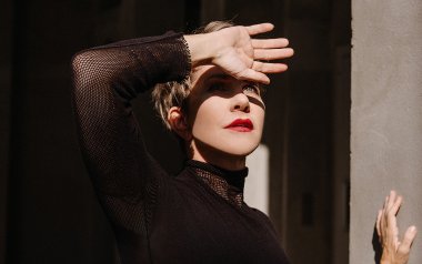 Joyce DiDonato's portrait. Her hand is held up in front of her forehead 