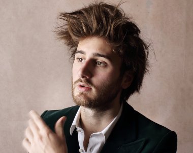 A portrait of a man, who is looking to the side, in front of a beige backsplash.