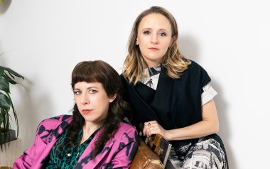 Missy Mazzoli and Ellen Reid posing together in front of a white wall