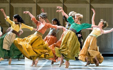 Dancers in colorful skirts are dancing with their hands up