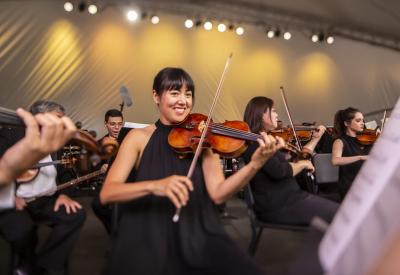 violinist smiling while playing in orchestra