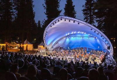 Orchestra on stage with audience clapping and blue and purple lighting on stage. 