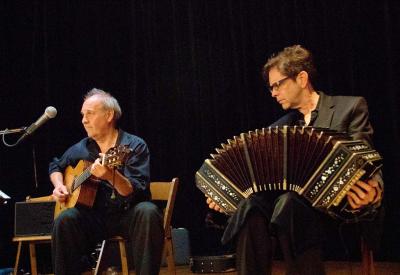 two men seated playing guitar and bandoneon