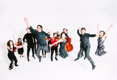 Image of Delirium Musicum musicians joyfully jumping in the air with their instruments