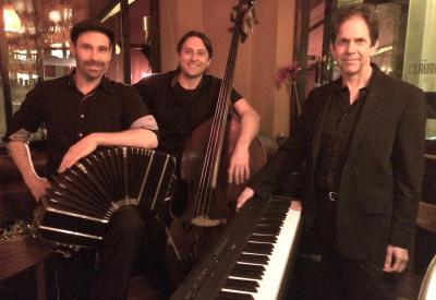 Three musicians: bandoneon player, bass player, pianist, all men, at night