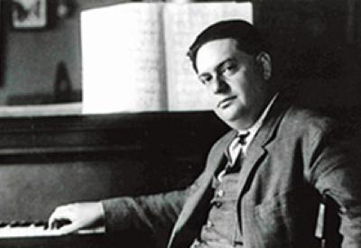 Darius Milhaud at piano with score.