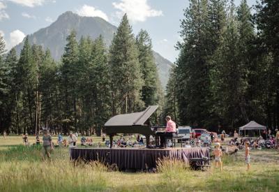 Hunter Noack plays the piano on a stage and audience members surround him and the piano listening to him play
