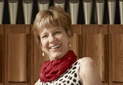 Concert organist Faythe Freese standing in front of organ pipes