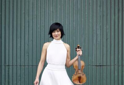 Jennifer Koh in a white dress, holding her violin