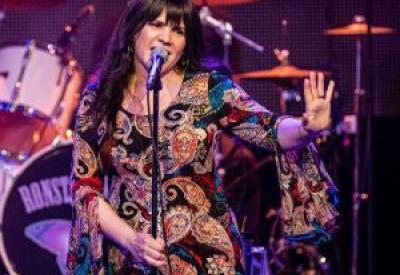 Gesenia holding her hand out with singing in a microphone as Linda Ronstadt.