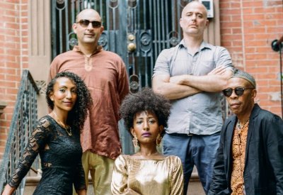 Alsarah & The Nubatones standing together in front of a brick wall.