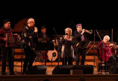 Itzhak Perlman and In the Fiddler's House performers on stage playing their instruments.