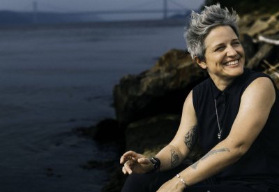Allison Miller in black on the shore of the ocean.