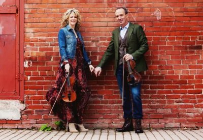 Natalie MacMaster and Donnell Leahy holding hands while holding their violins.