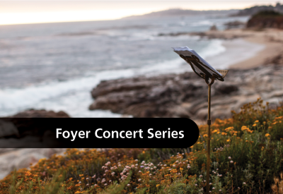 A music stand on a path above the beach with the text, "Foyer Concert Series."