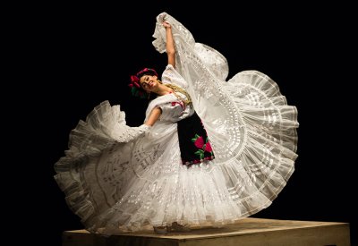 Dancer with a big white skirt is holding the skirt while twirling