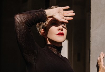Joyce DiDonato's portrait. Her hand is held up in front of her forehead 