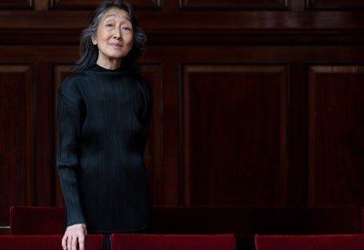 Mitsuko Uchida posing in front of a wooden wall