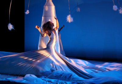 Dancer in a white dress dancing in a bule setting