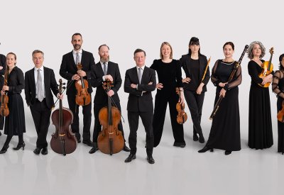 The English Concert holding their instruments in front of a white back drop