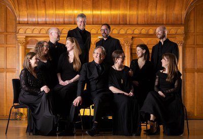 The Tallis Scholars posing in front of a wooden ornate wall