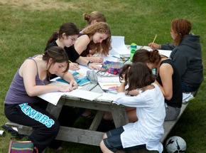Students composing at a picnic table